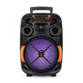 A black portable karaoke speaker with orange accents and a purple front grille stands next to its white retail box. The speaker has multiple speakers, a control panel, and a handle on top.
